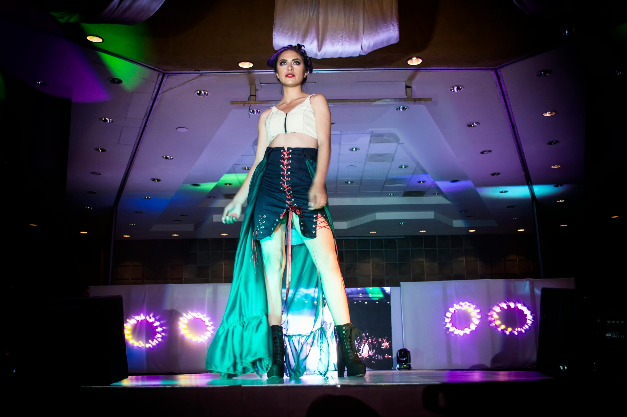 Fashion model strutting on a runway during a glamorous evening event with vibrant lights in Morelia, Mexico.